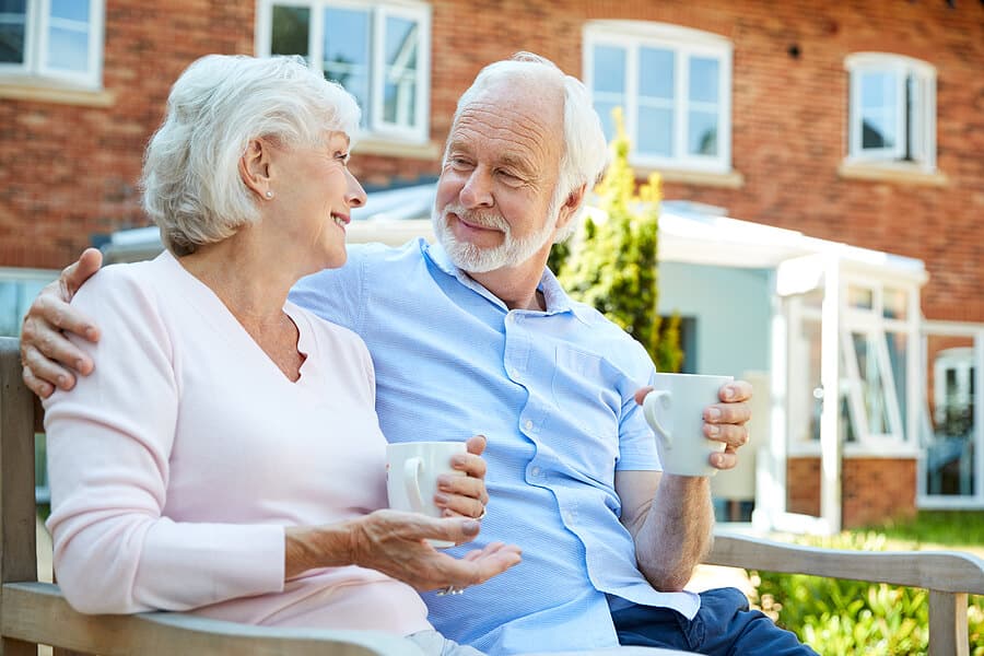 Happy senior couple enjoys coffee outside at their assisted living community.